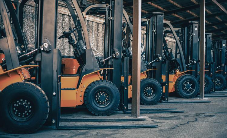 Oranje vorkheftrucks op een rij in een loods